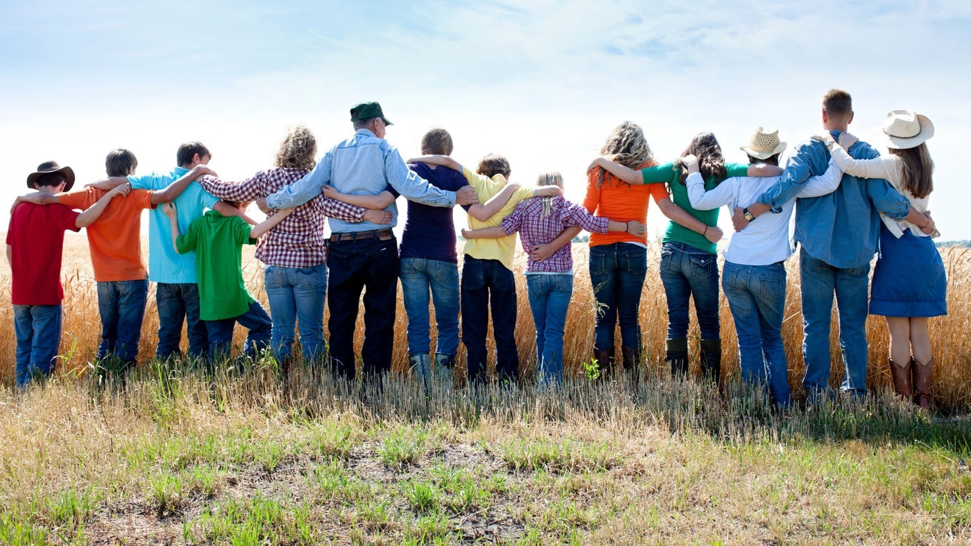 Product support page image showing a group of people standing in a field with arms around each other, symbolizing teamwork and community.